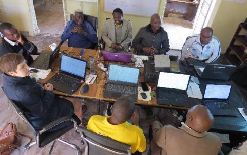 Toka-Leya translation team working around a table with laptops