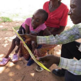 Vincent sharing a Toka-Leya literacy booklet with a young girl and her grandmother